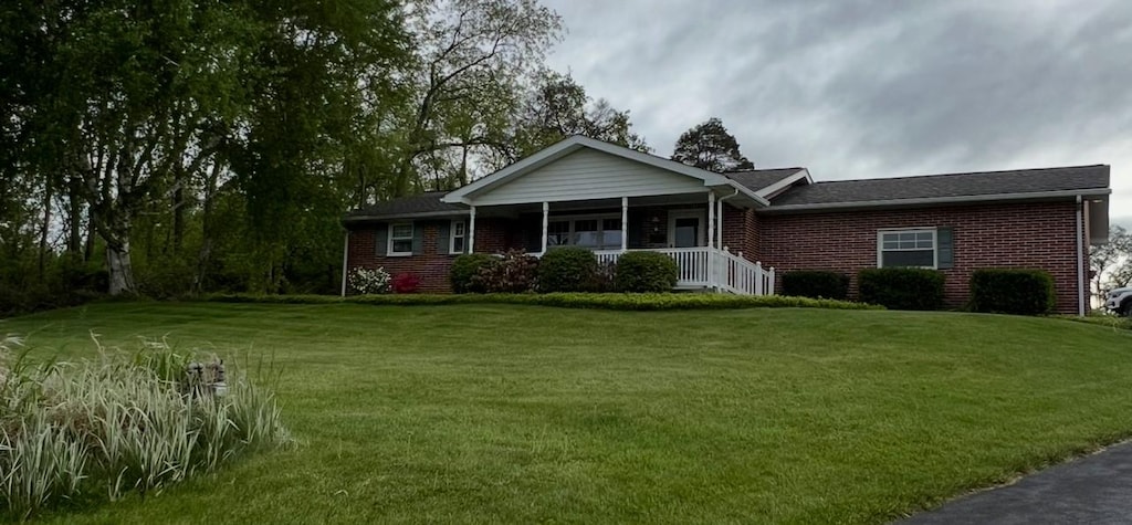 ranch-style house with covered porch, a front yard, and brick siding