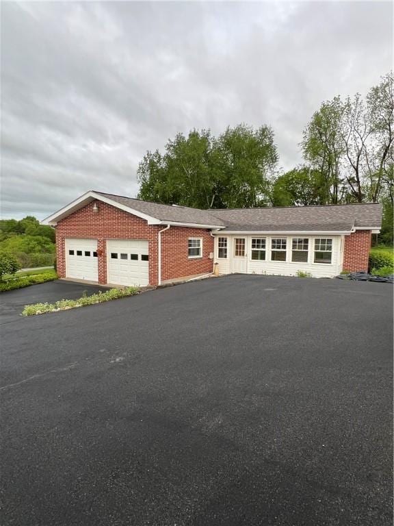 view of front facade featuring asphalt driveway, a garage, and brick siding