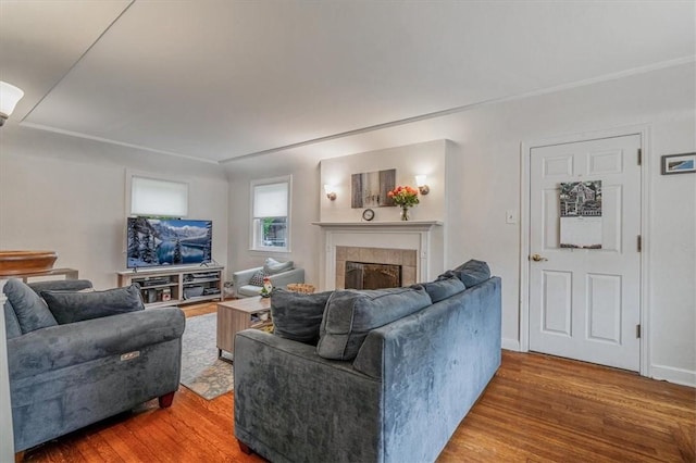 living room featuring wood finished floors, a tile fireplace, and baseboards