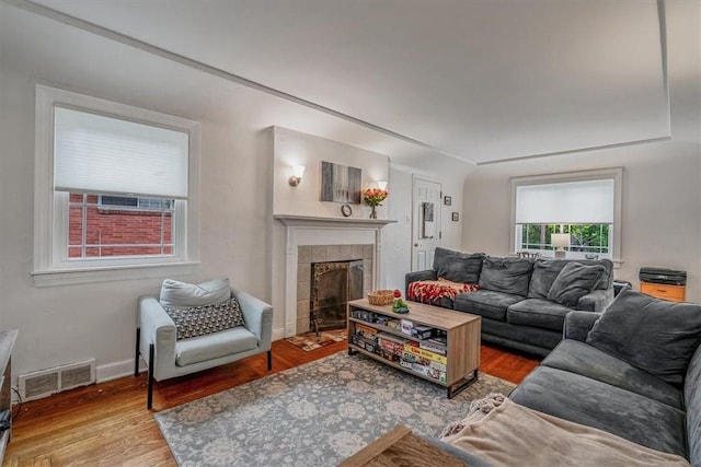 living area featuring wood finished floors, a tile fireplace, and baseboards