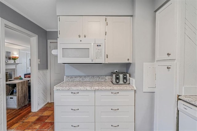 kitchen featuring white appliances, white cabinets, light stone countertops, crown molding, and a fireplace