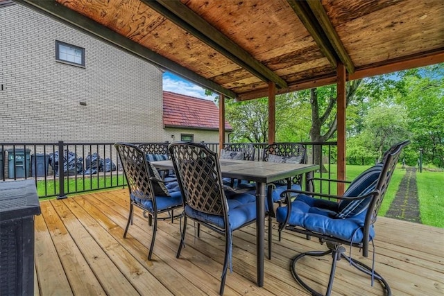 wooden deck with outdoor dining space and a lawn
