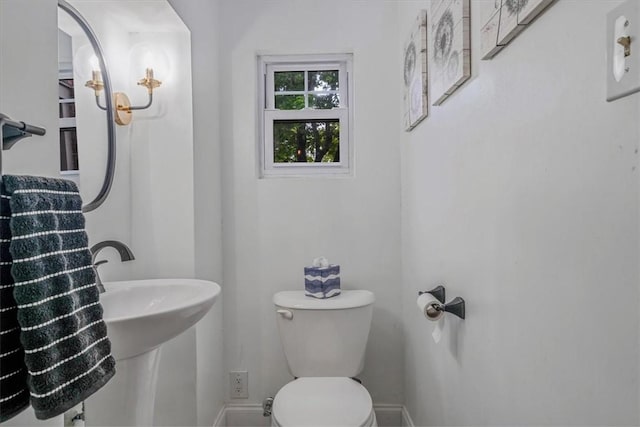 bathroom with toilet, baseboards, and a sink