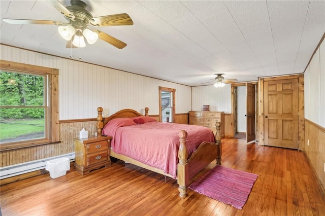 1770 Perry Hwy, Muddy Creek Twp, PA 16051 - bedroom featuring wood finished floors, wooden walls, a baseboard heating unit, a ceiling fan, and wainscoting