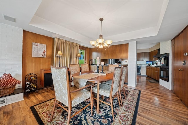 257 Penhurst Dr, Wilkins Twp, PA 15235 - dining room featuring a tray ceiling, a chandelier, light wood-type flooring, and wood walls