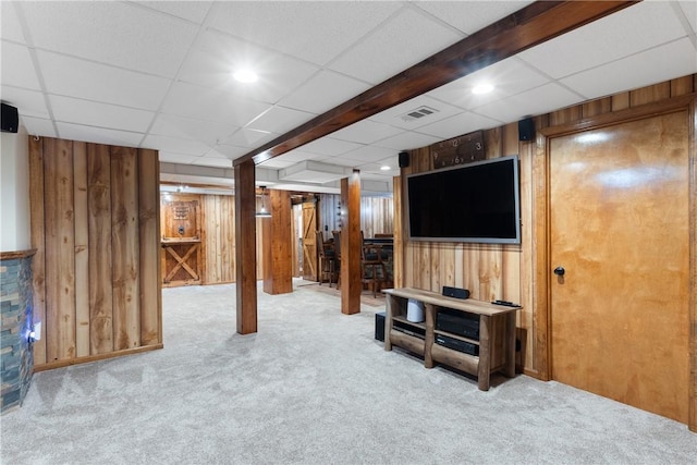finished basement with wooden walls, carpet floors, and a paneled ceiling