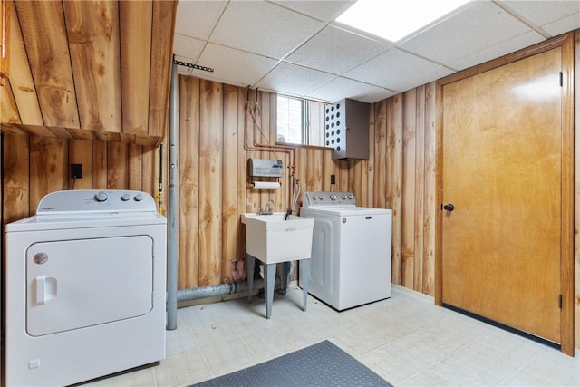 laundry area featuring independent washer and dryer, wooden walls, tile patterned floors, and a sink
