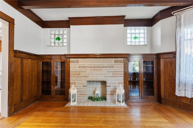 unfurnished living room featuring wood finished floors, a fireplace, and beamed ceiling