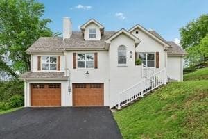 view of front of home featuring a garage, a chimney, and driveway