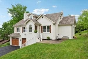 traditional-style house with driveway, a garage, a front lawn, and a chimney