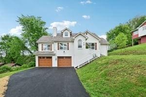 view of front of house featuring an attached garage, asphalt driveway, a chimney, and a front lawn