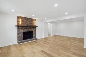 unfurnished living room with wood finished floors, a fireplace, recessed lighting, and baseboards