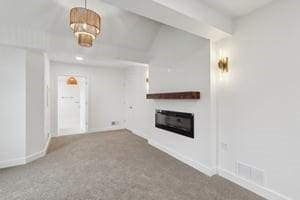 unfurnished living room with a glass covered fireplace, carpet flooring, and baseboards
