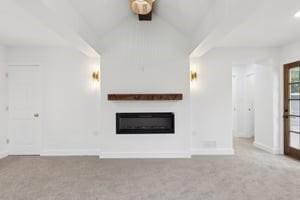 unfurnished living room featuring carpet floors, a glass covered fireplace, lofted ceiling, and baseboards