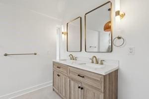 full bath featuring double vanity and baseboards