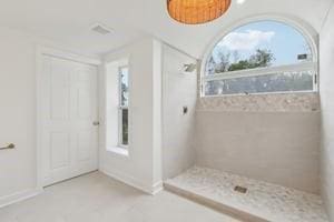 full bath featuring tiled shower and baseboards