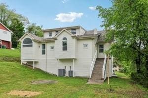 back of property with a lawn and stairs