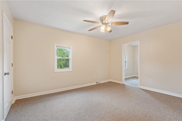 carpeted spare room featuring a ceiling fan and baseboards