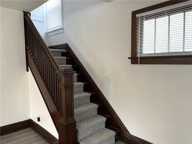 stairway featuring healthy amount of natural light, baseboards, and wood finished floors