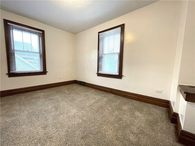 unfurnished room with healthy amount of natural light, carpet floors, and baseboards