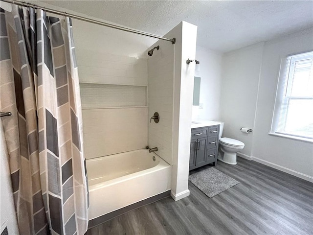 bathroom featuring wood finished floors, vanity, toilet, baseboards, and shower / tub combo with curtain