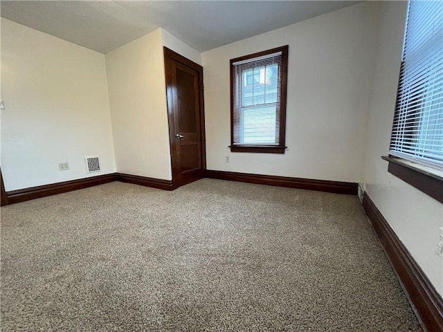 carpeted empty room featuring baseboards