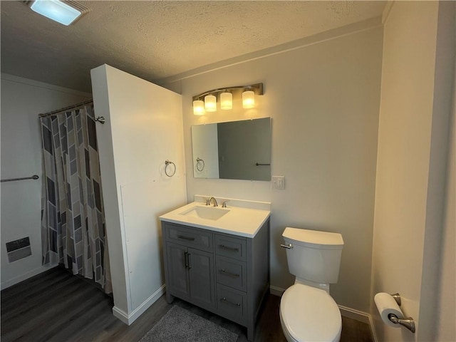 full bath with wood finished floors, vanity, toilet, baseboards, and a textured ceiling