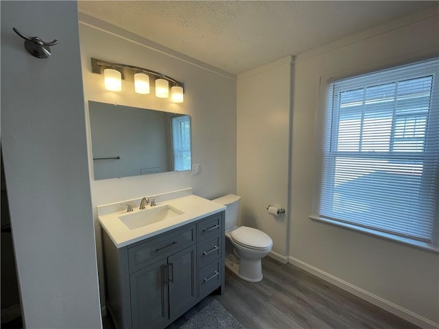 bathroom with wood finished floors, plenty of natural light, toilet, a textured ceiling, and baseboards
