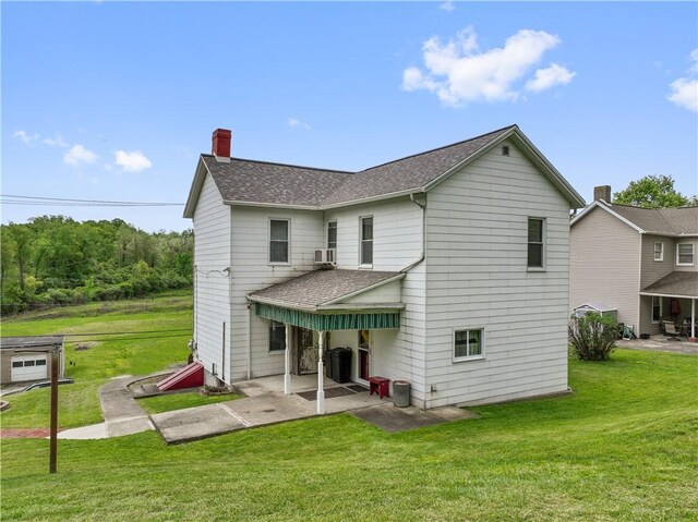 back of house with roof with shingles, a chimney, a patio, a lawn, and cooling unit
