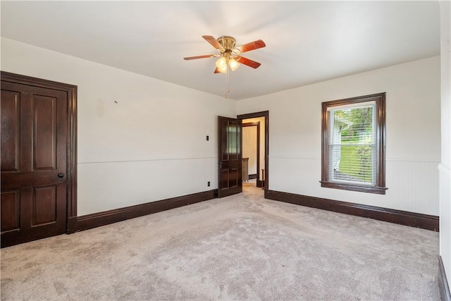unfurnished room with carpet, ceiling fan, wainscoting, and baseboards