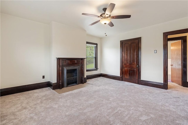 unfurnished living room featuring carpet, a ceiling fan, baseboards, and a fireplace with flush hearth