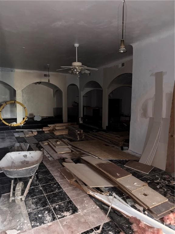 miscellaneous room with arched walkways and a ceiling fan