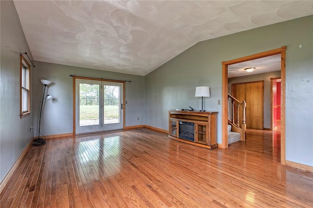 5569 Camerons Rd, Brush Val/Buffington, PA 15748 - unfurnished living room featuring wood-type flooring, stairs, baseboards, vaulted ceiling, and a glass covered fireplace