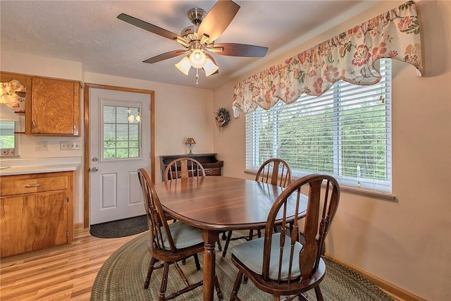 dining room with light wood finished floors, ceiling fan, and baseboards