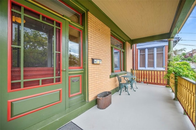 view of exterior entry featuring a porch and brick siding