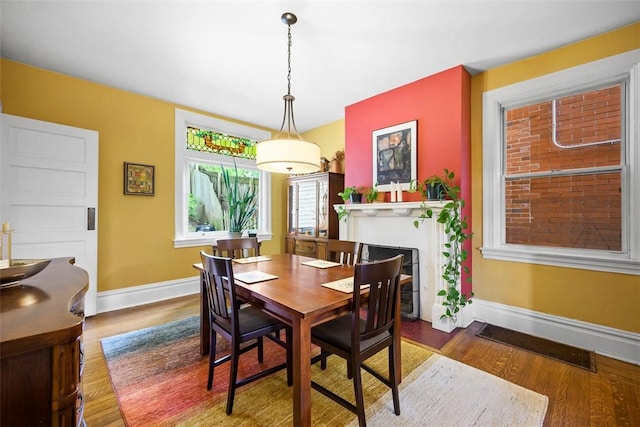 dining room featuring wood finished floors, baseboards, and a fireplace