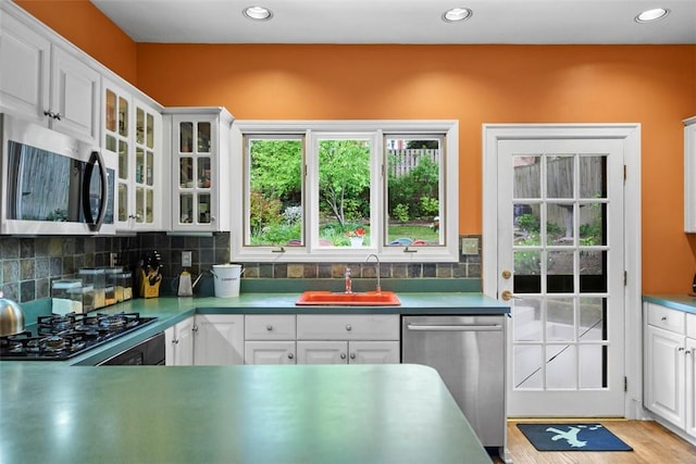 kitchen with stainless steel appliances, a sink, white cabinetry, recessed lighting, and decorative backsplash