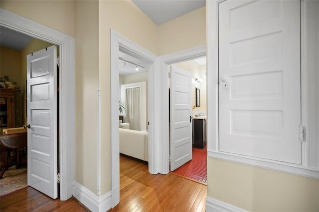 hall with wood-type flooring and baseboards