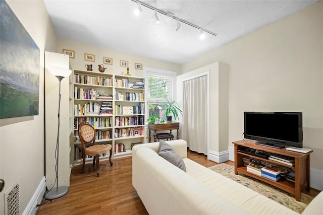 living room with rail lighting, wood finished floors, and baseboards