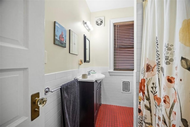 bathroom with tile walls, a wainscoted wall, vanity, and curtained shower