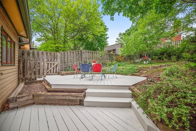wooden terrace with a fenced backyard and outdoor dining area