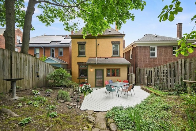 back of property featuring a fenced backyard, a deck, and outdoor dining space