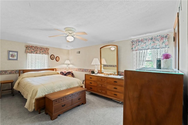 bedroom featuring light carpet, a textured ceiling, and ceiling fan