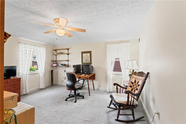 carpeted home office featuring baseboards, a ceiling fan, and a textured ceiling