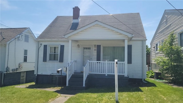 bungalow-style house with a porch, a front yard, a chimney, and central air condition unit