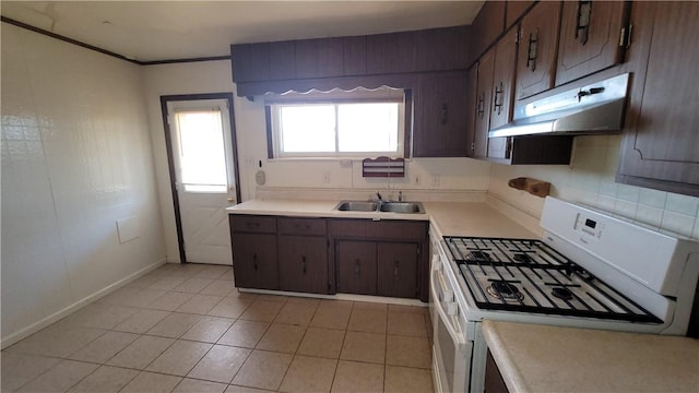 kitchen with white gas range, a sink, under cabinet range hood, light countertops, and light tile patterned flooring