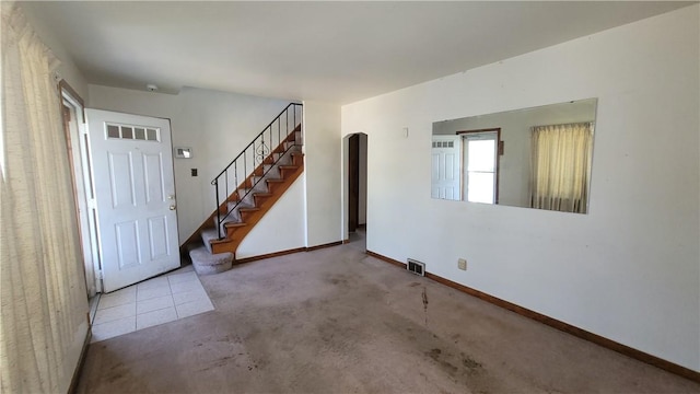 carpeted spare room with stairs, baseboards, and arched walkways