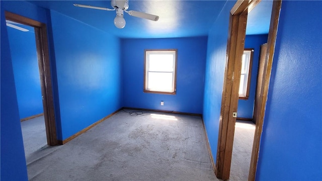 carpeted empty room with baseboards and a ceiling fan