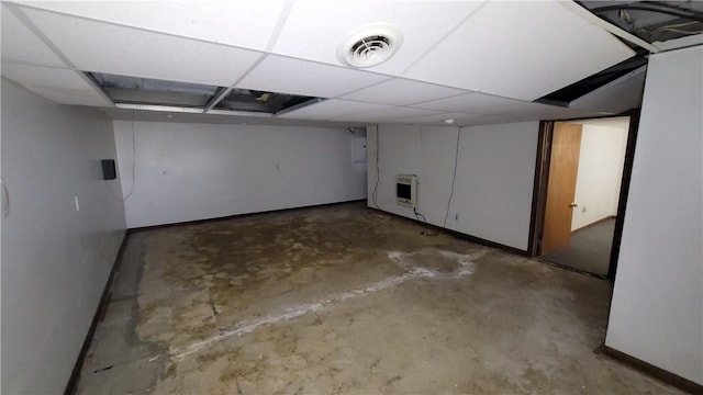 finished below grade area with heating unit, baseboards, and a paneled ceiling