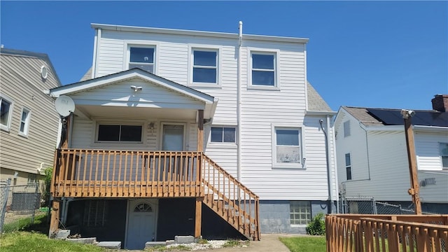 rear view of house featuring a deck, stairs, and fence